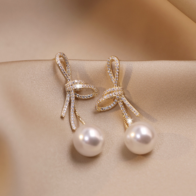 Pendientes de perlas con lazo brillante en dorado